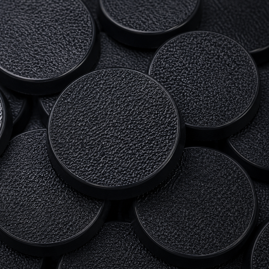 Close-up of black 40mm round plastic miniature bases showing textured top surfaces for tabletop wargaming, RPG miniatures, conversions, and hobby basing projects.