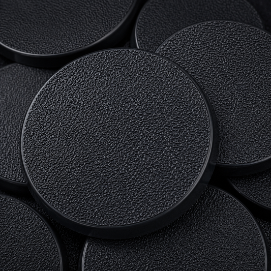 Close-up of black 50mm round plastic miniature bases showing textured top surfaces for tabletop wargaming, RPG monsters, conversions, and hobby basing projects.
