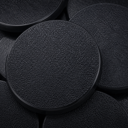 Close-up of black 60mm round plastic miniature bases showing textured top surfaces for tabletop wargaming, RPG monsters, conversions, and hobby basing projects.