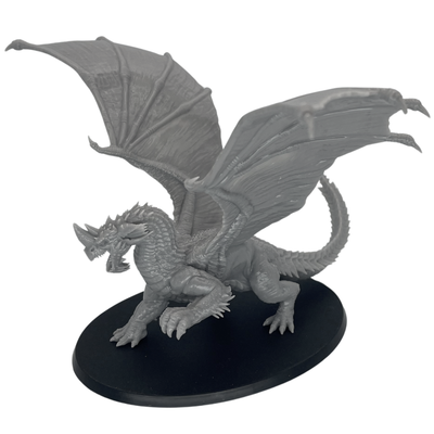 Unpainted Adult Blue Dragon miniature shown from the front with raised wings, horned head, and large oval base.