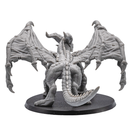 Back view of the unpainted Adult Red Dragon miniature showing folded wings, long tail, and textured scales.