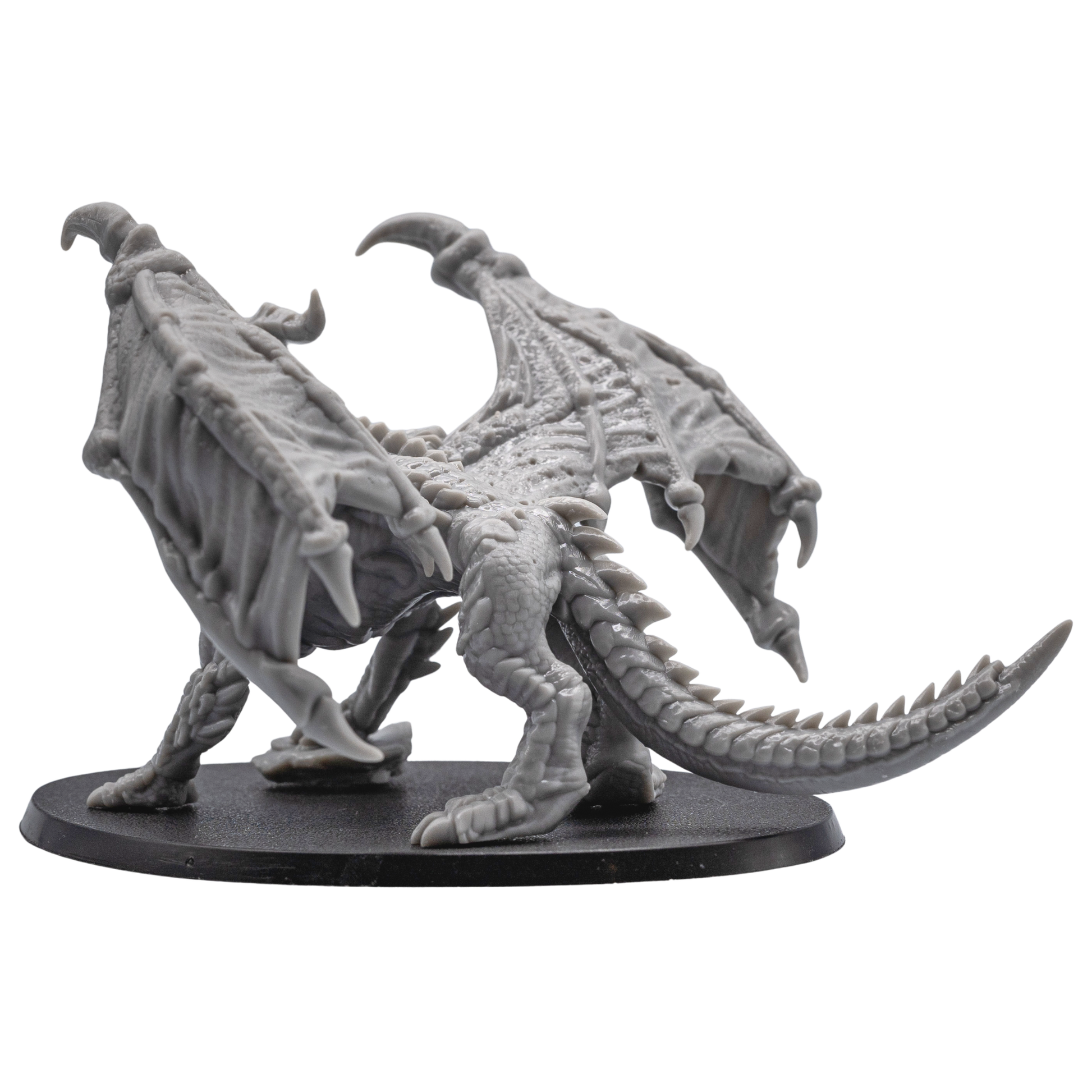 Left side view of the unpainted Adult Red Dragon miniature showing wing membrane, horns, claws, and tail.