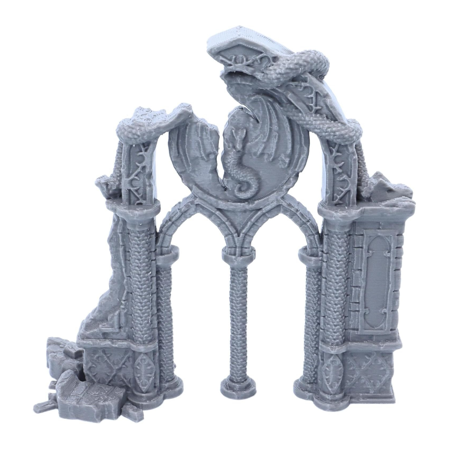 Front view of the unpainted Dragon Archway showing the central dragon emblem, columns and ruined stonework