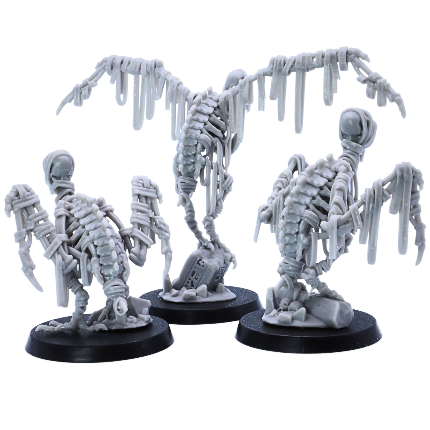 Rear view of three unpainted Egyptian Vulture miniatures showing skeletal backs, wrapped wings, scenic bases, and bone details.