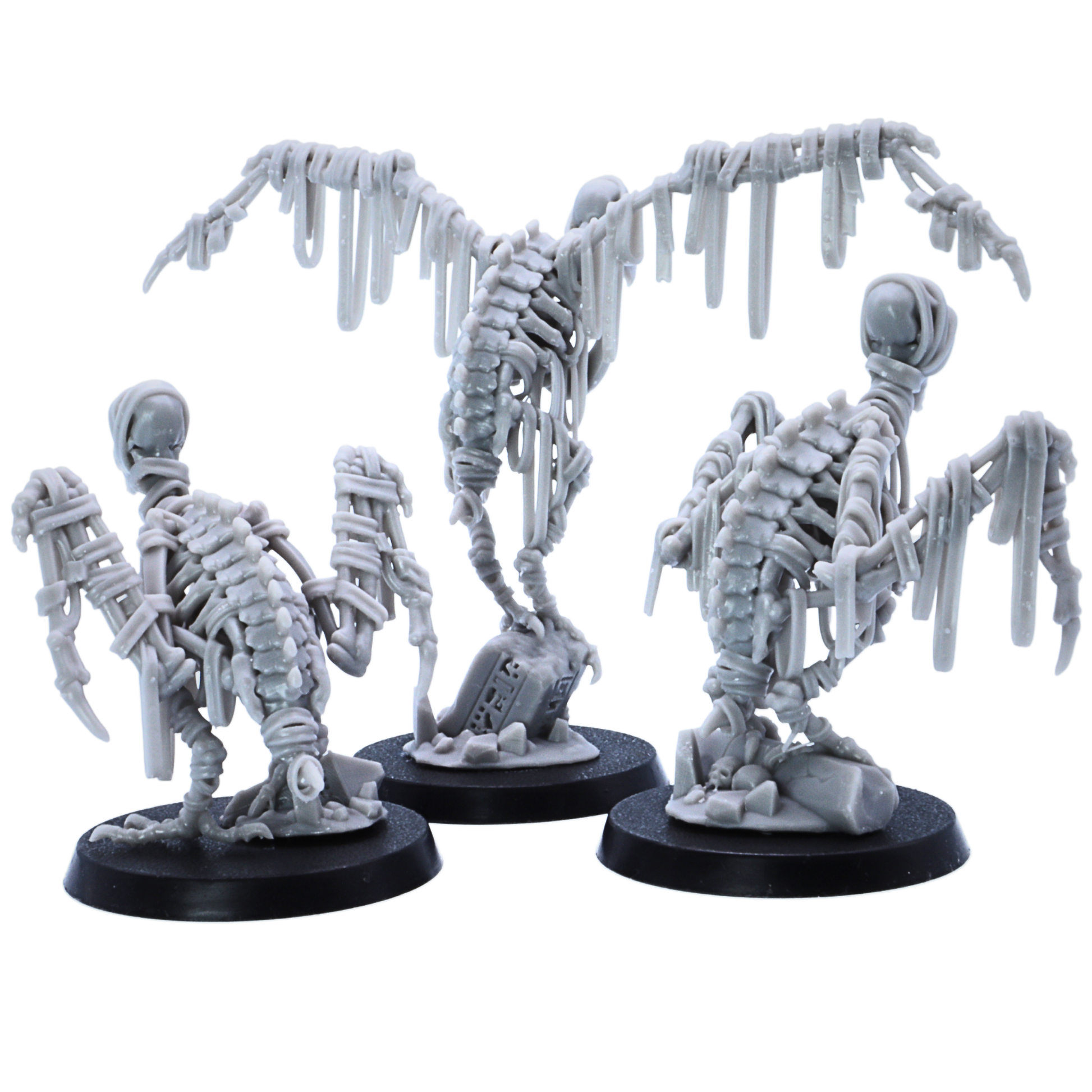 Rear view of three unpainted Egyptian Vulture miniatures showing skeletal backs, wrapped wings, scenic bases, and bone details.