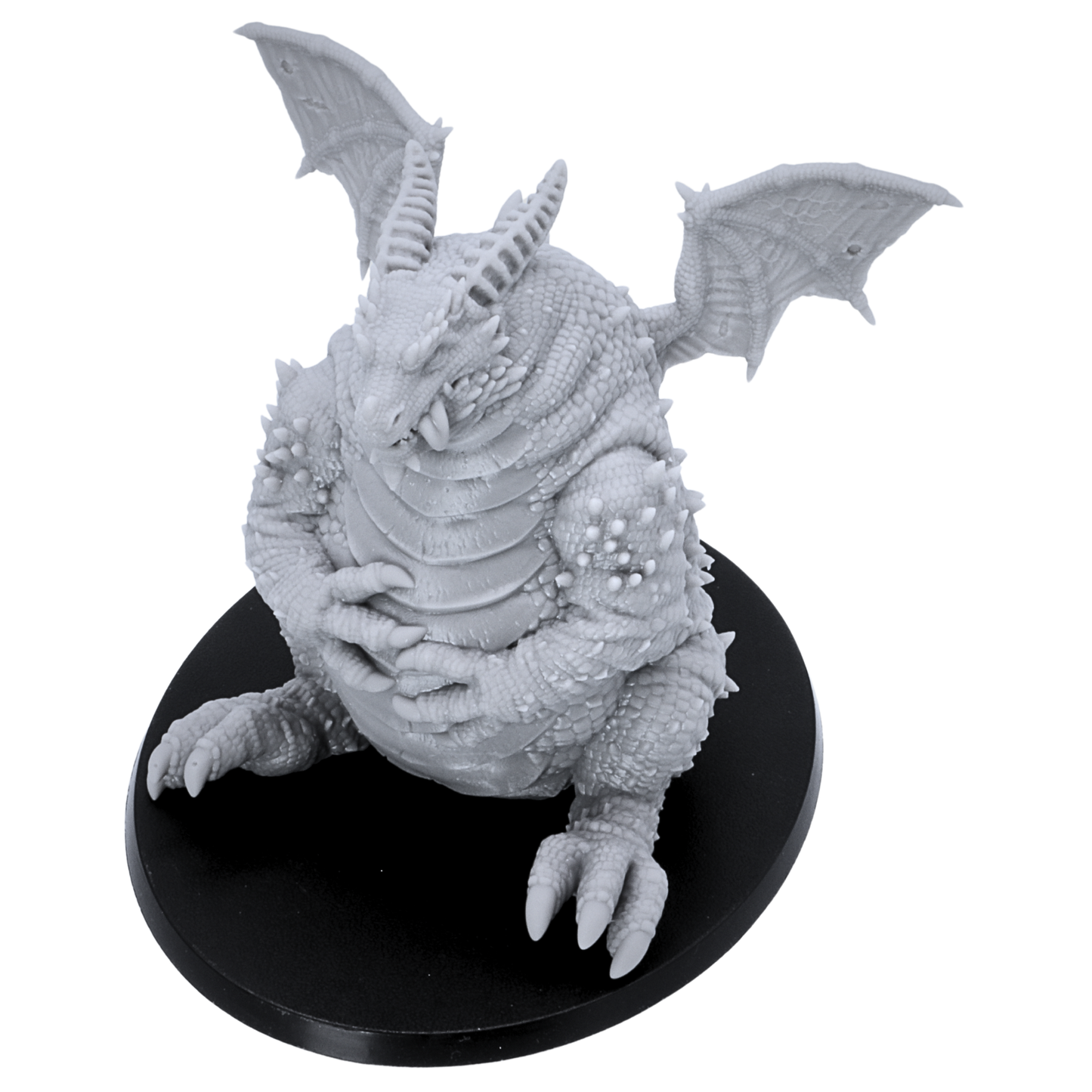 Top-down view of the unpainted Fat Dragon Sitting miniature showing wings, horns, scales, and oval base.