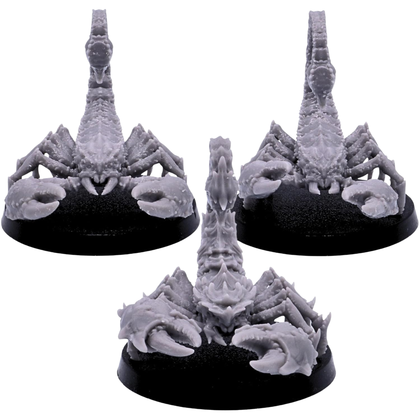 Front views of three unpainted Scorpion miniatures showing massive pincers, plated heads, segmented bodies, and upright stinging tails.