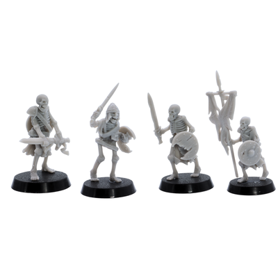 Unpainted skeletal warriors showing four different undead fighter poses with swords, shields, armour, and battle standard.