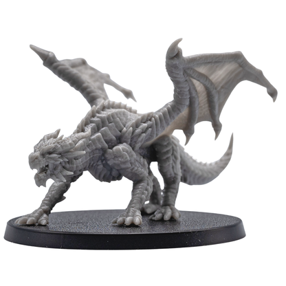 Action pose view of an unpainted Young Red Dragon miniature with raised wings, open jaws, claws, and detailed fantasy creature sculpt.