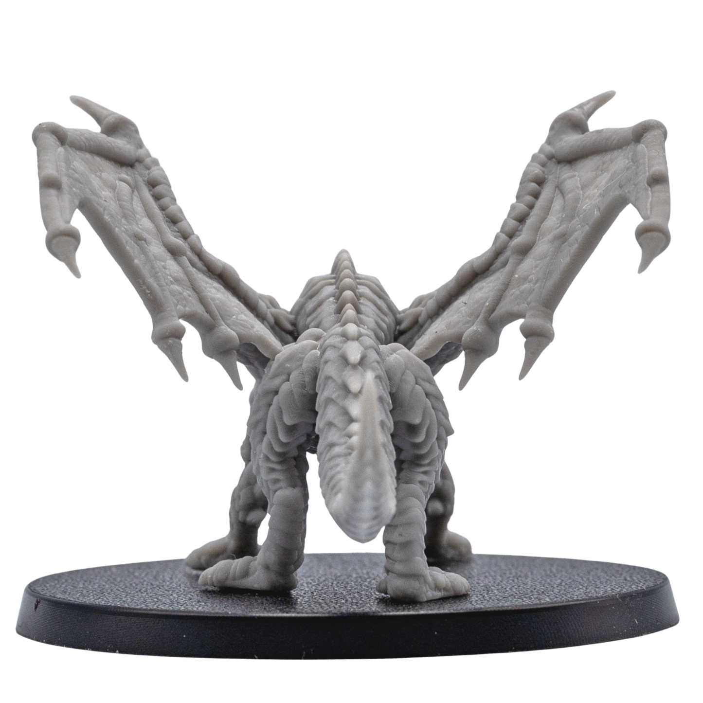 Rear view of an unpainted Young Red Dragon miniature showing spread wings, scaled back, long tail, and round base.
