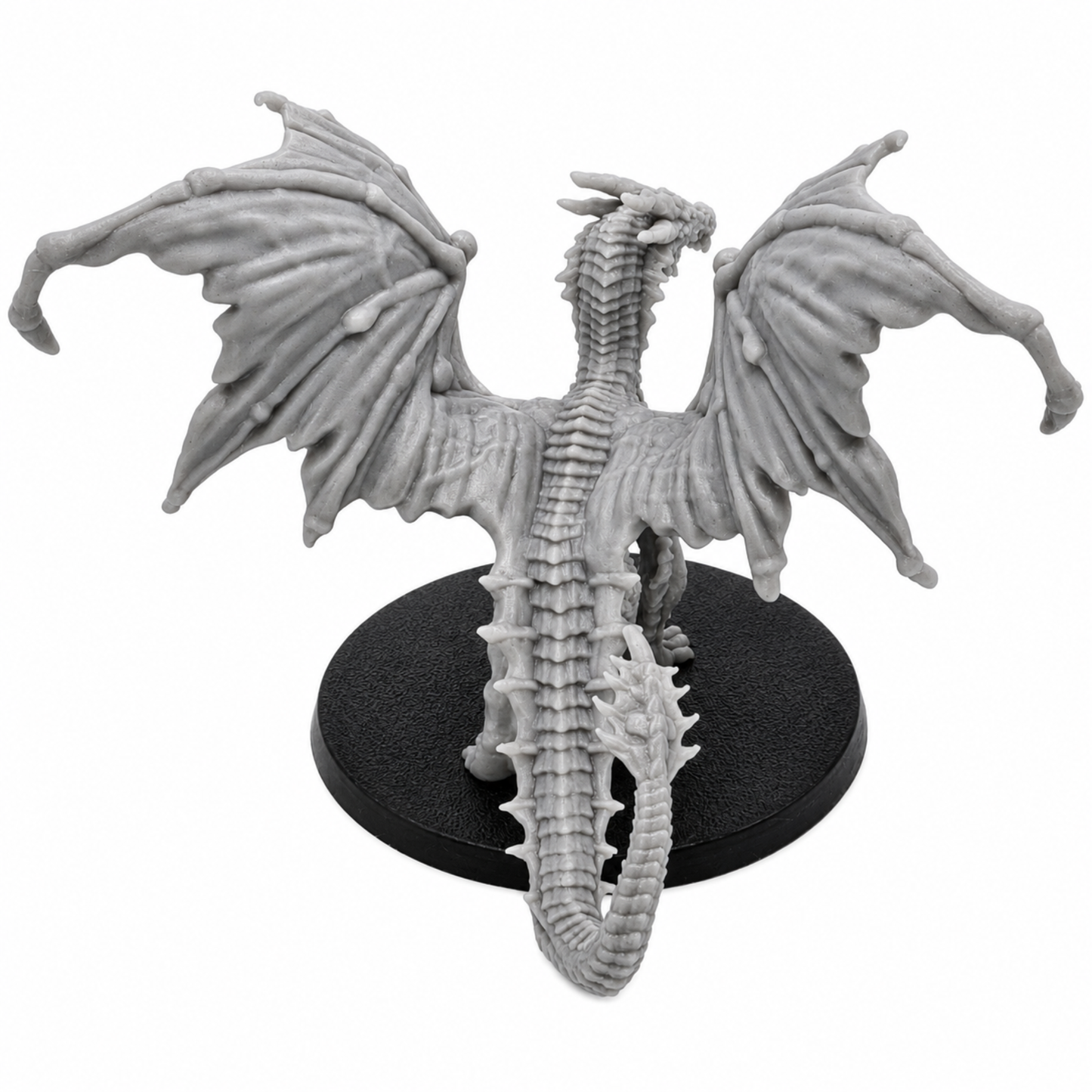 Rear view of an unpainted Young Yellow Dragon resin miniature showing broad wings, scaled back, long tail, and round base.
