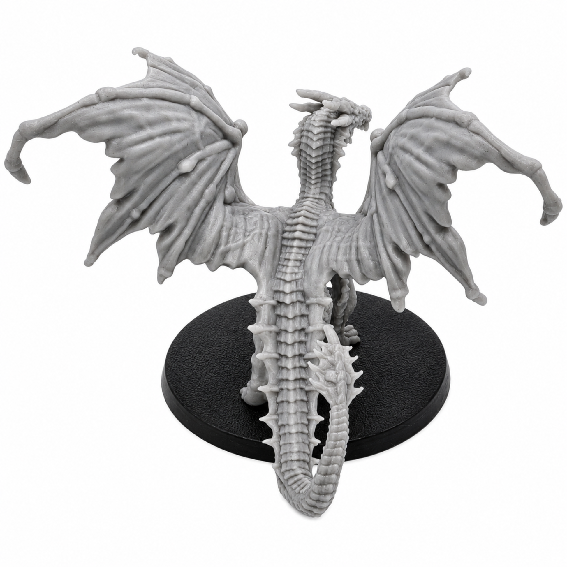 Rear view of an unpainted Young Yellow Dragon resin miniature showing broad wings, scaled back, long tail, and round base.