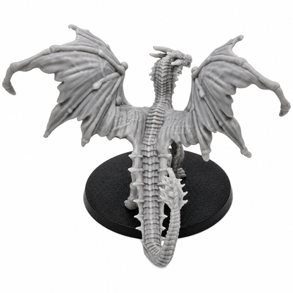 Rear view of an unpainted Young Yellow Dragon resin miniature showing broad wings, scaled back, long tail, and round base.